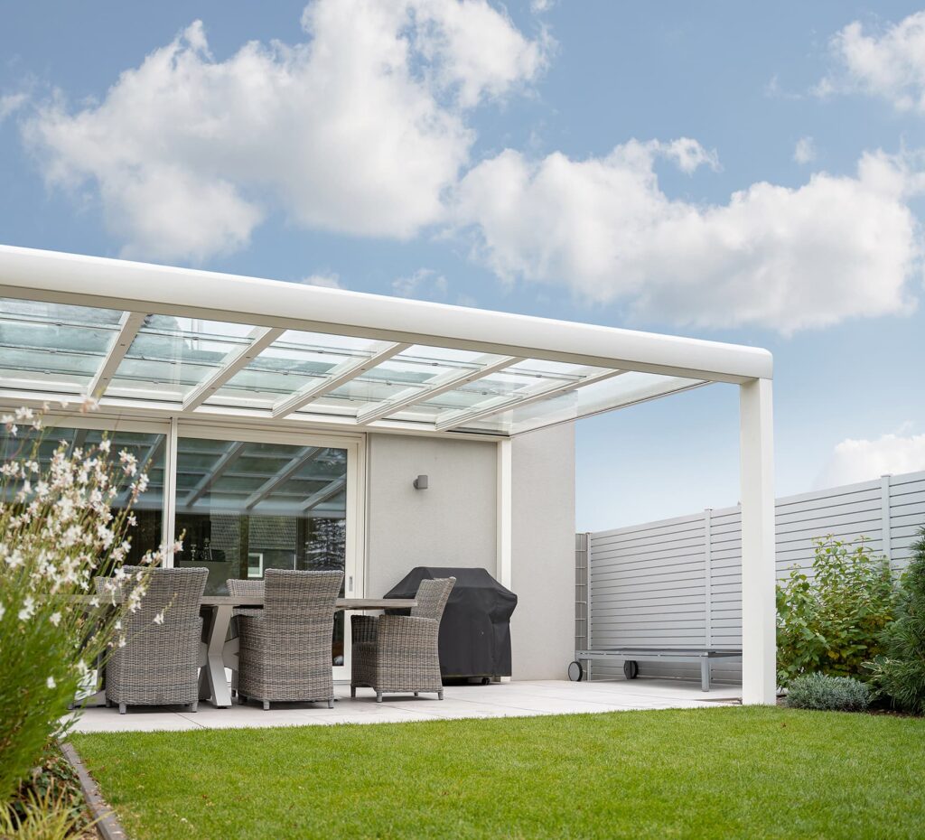 Eine weiße Terrassenüberdachung an einem grauen Haus.